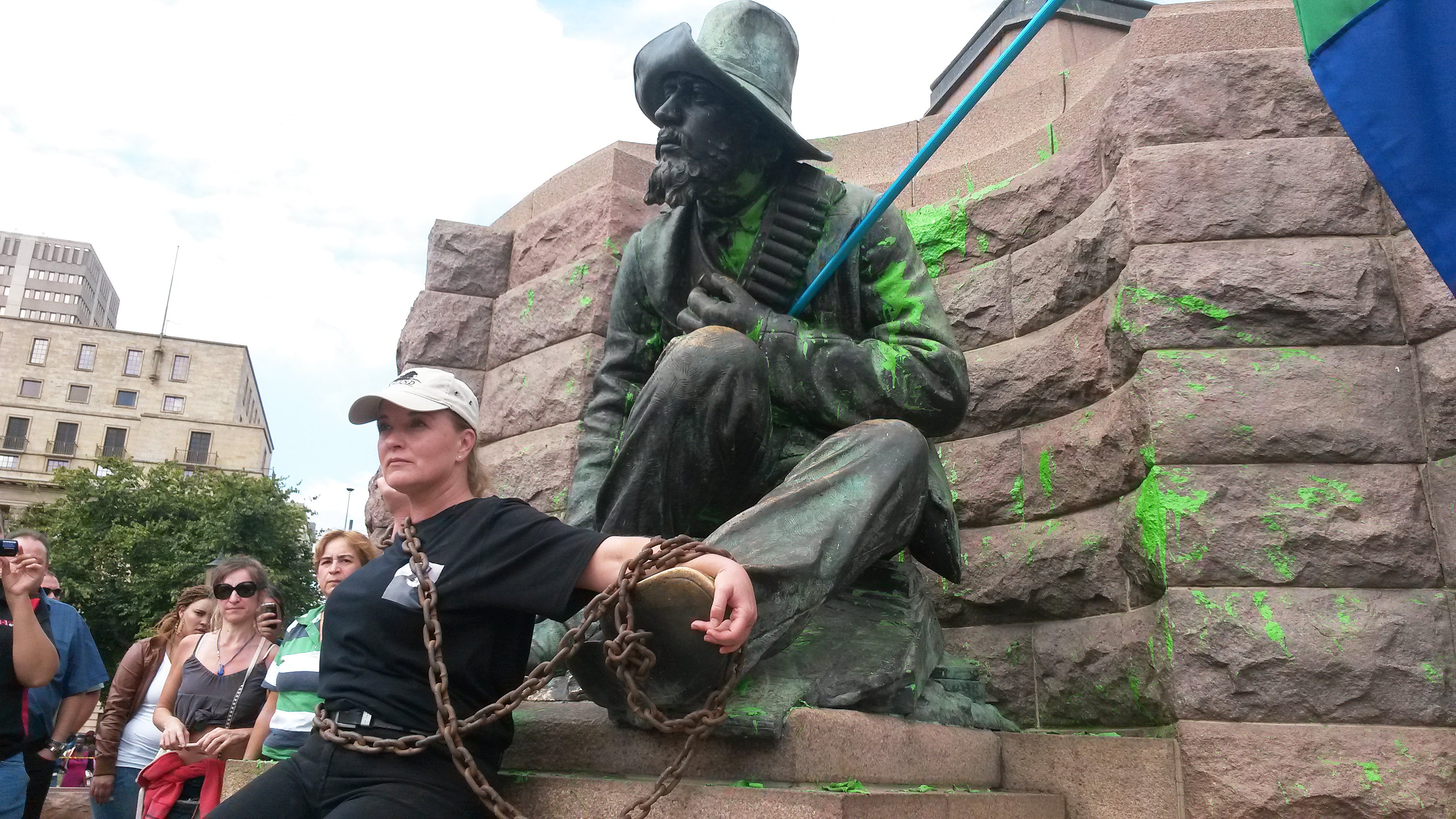 Tegenreactie. Een demonstrante heeft zich vastgeketend aan de voet van het beeld van Paul Kruger in Pretoria, nadat dit eerder door andere activisten is beklad, 8 april 2015 (Foto: News24/Ockert de Villiers)