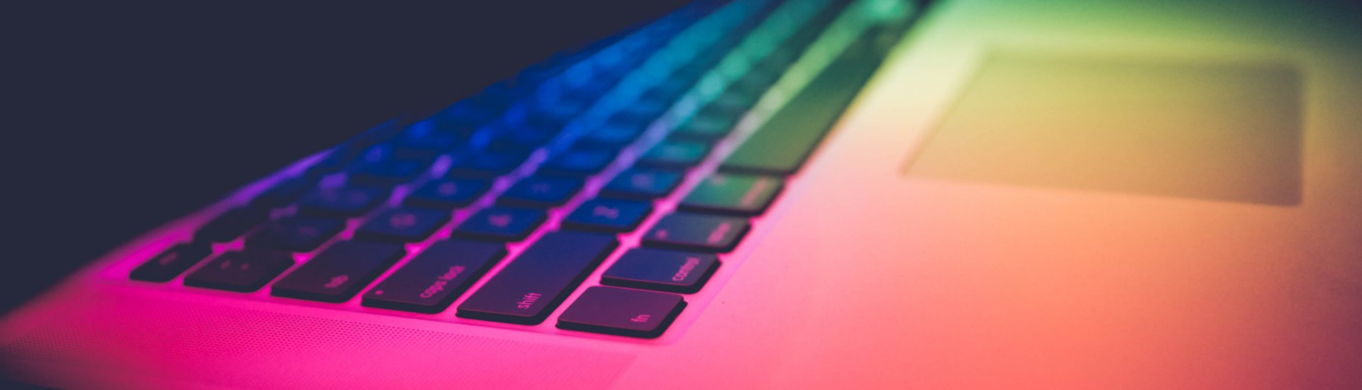 Foto van een opengeslagen laptop in kleurig licht. (Foto: Unsplash.com | Igor Ovsyannyko)