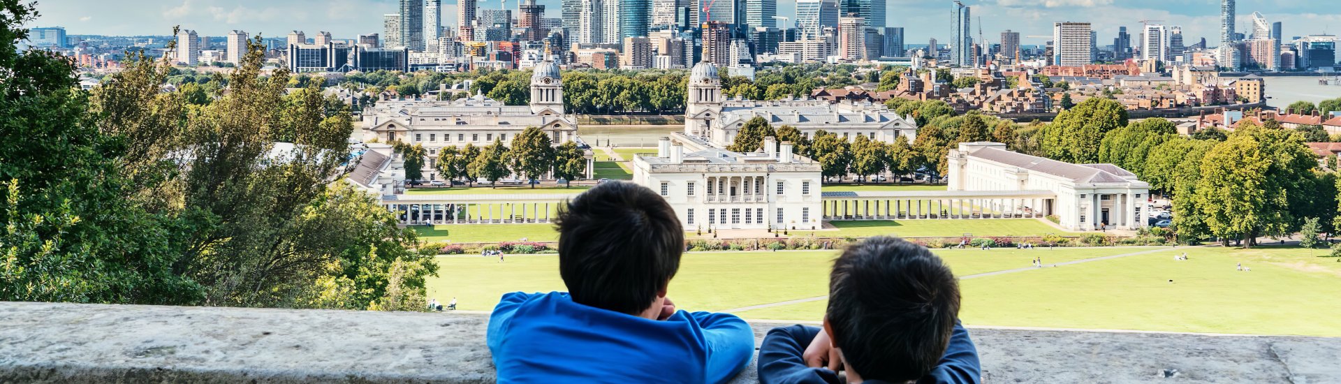 Twee jongens kijken over een muur naar Greenwich, tegen de achtergrond van Londen.
