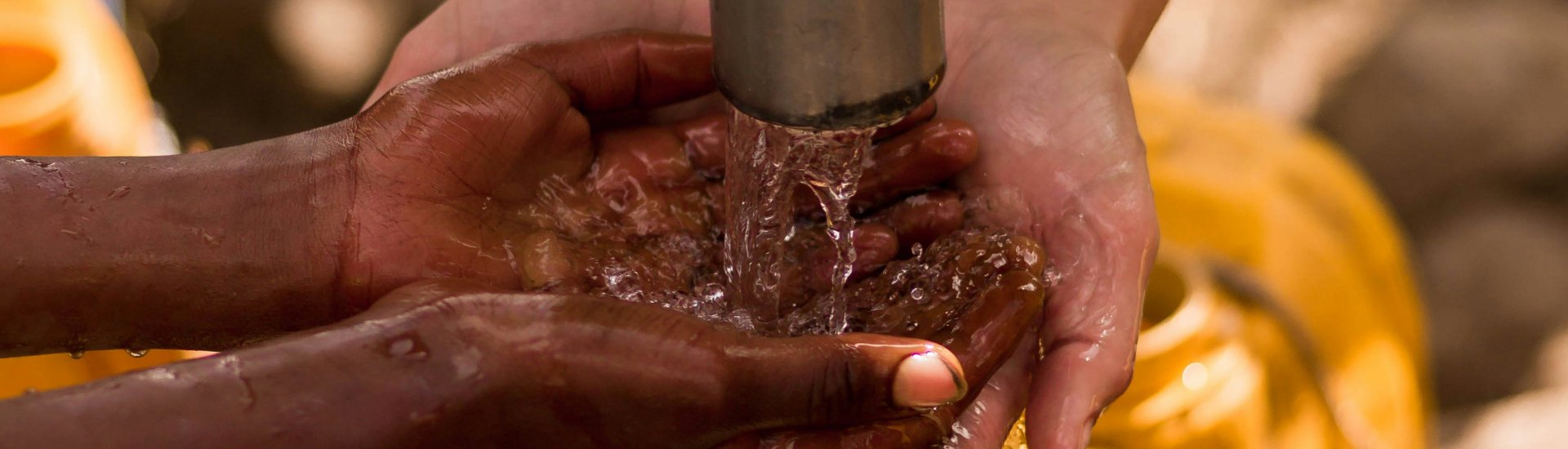 Een kind wast de handen onder een buitenkraan