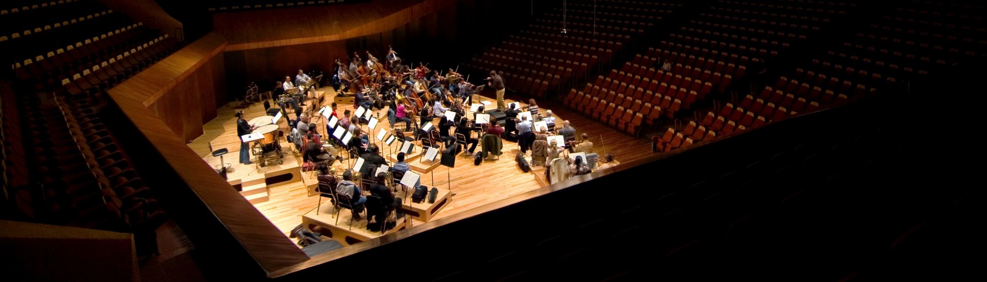 Een orkest oefent in een lege zaal.