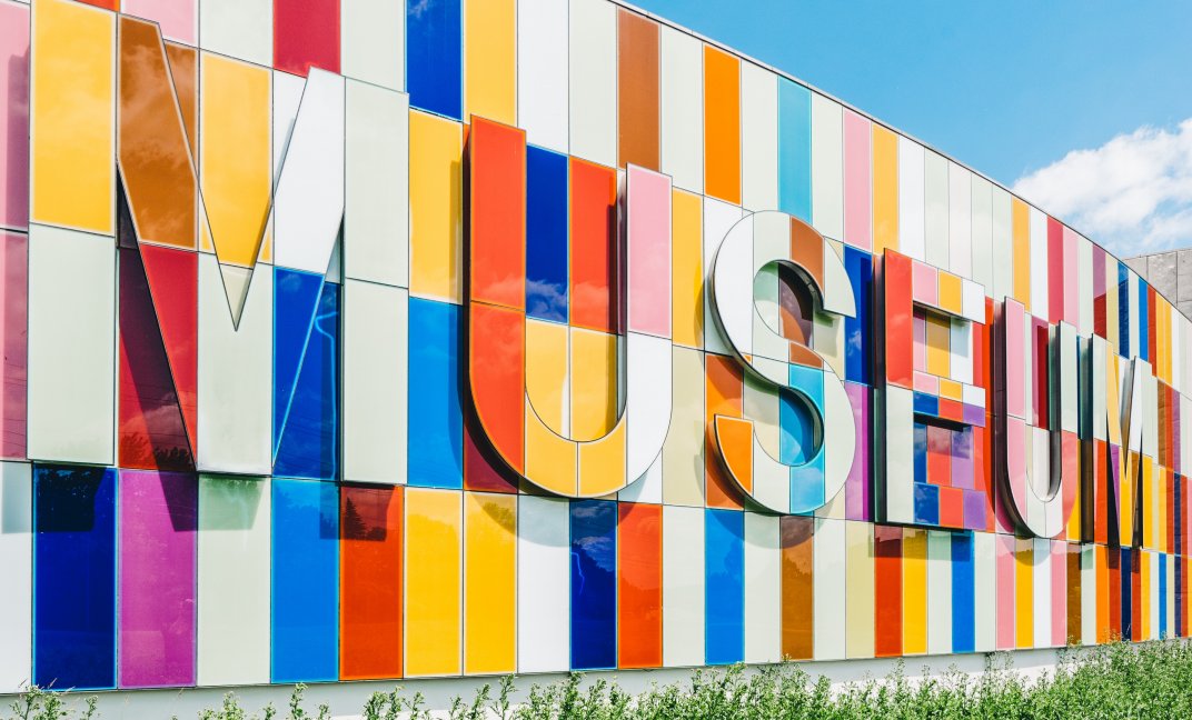Een kleurige muur met daarop de tekst 'museum'. (Foto: Unsplash.com | Scott Webb)