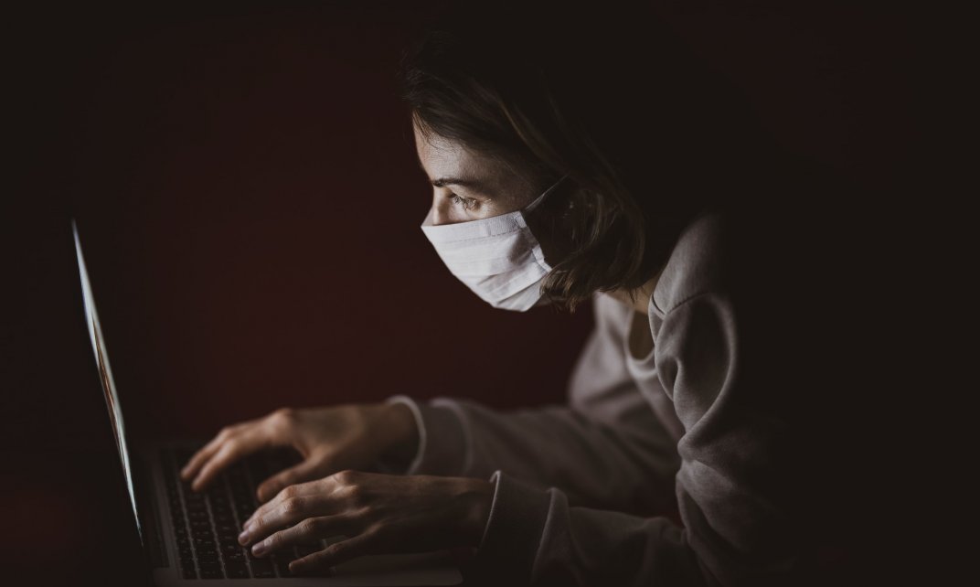 Vrouw met mondkapje voor typt op een laptop. (Foto: Engin Akyurt | CC/Unsplash.com)
