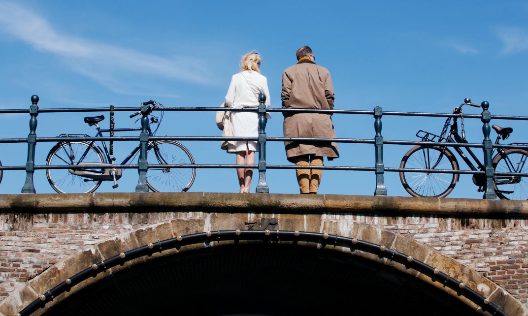 Twee mensen staan op een brug in Amsterdam.