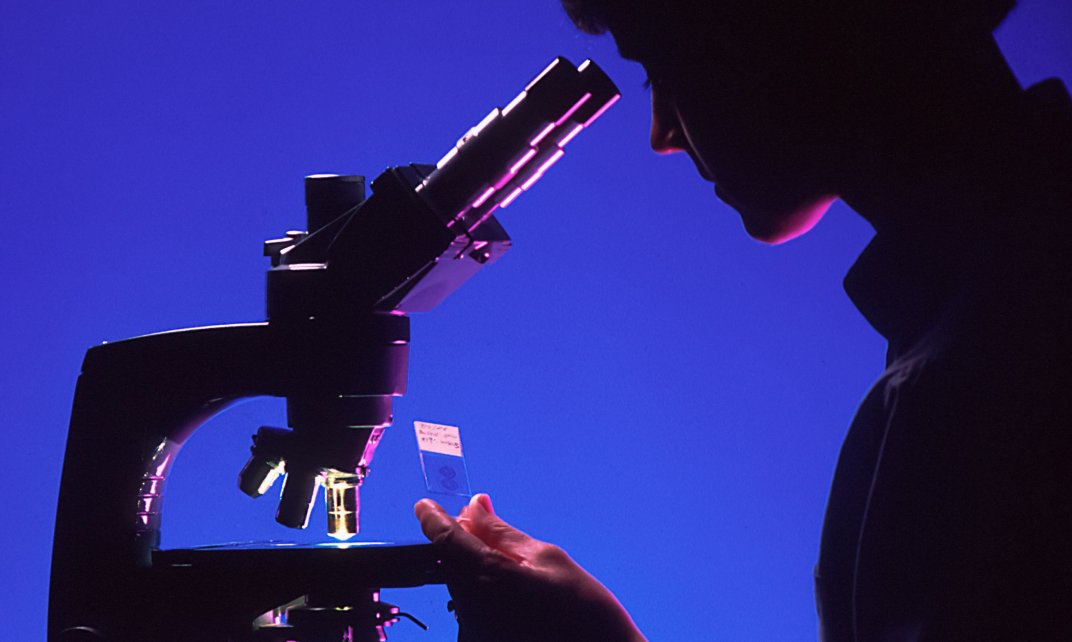 Vrouwelijke wetenschapper doet onderzoek met een microscoop.