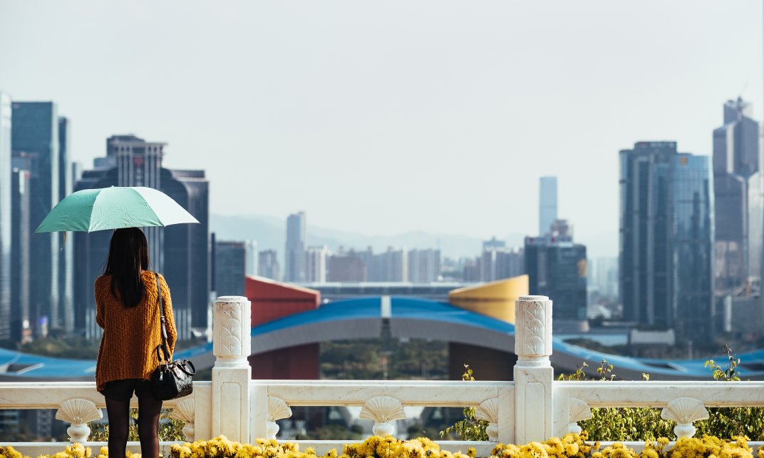 Een vrouw kijkt uit over het stadslandschap van de Chinese stad Shenzhen. (Foto: Unsplash.com | Robert Bye)